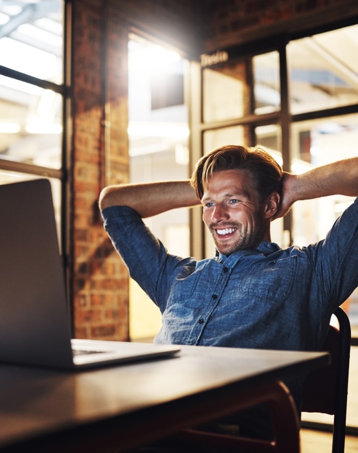 Another deadline met with ease. a handsome young male designer looking relaxed while working late in his office